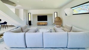 Ein modernes Wohnzimmer mit Eckcouch, Flachbildfernseher, Couchtisch und einer Treppe.