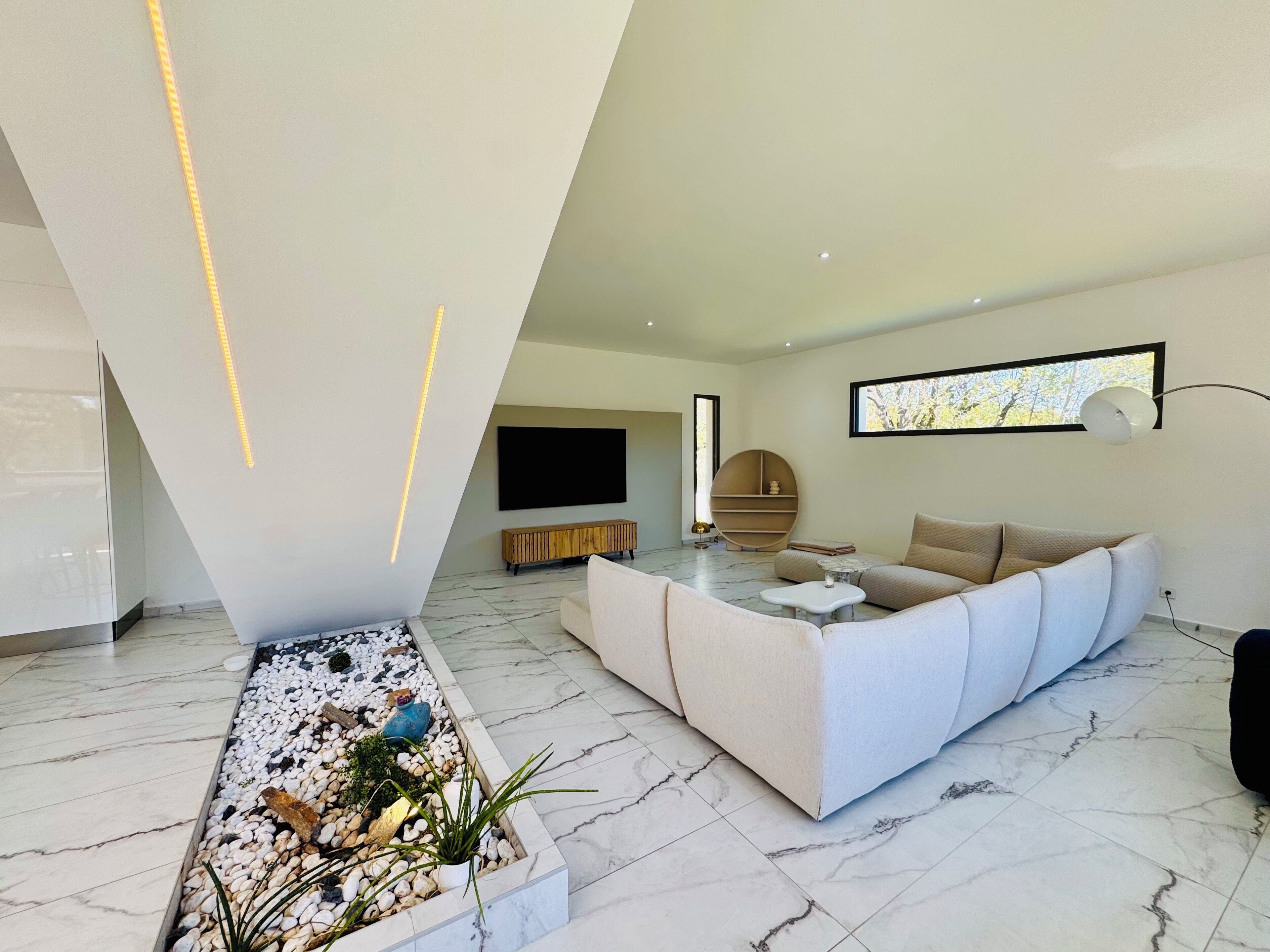 Un soggiorno moderno con un divano, una televisione e un'elegante composizione di piante decorative.