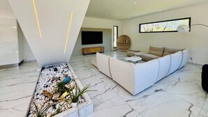 Ein modernes Wohnzimmer mit einer Couch, einem Fernseher und einer dekorativen Pflanzenanordnung.