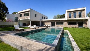 Ein modernes, zweistöckiges Haus mit Schwimmbad, Steinhausfassade und einer Terrasse.