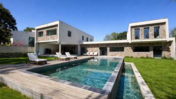 Een modern herenhuis met zwembad, stenen gevel en terras.