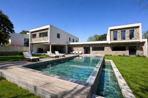 Ein modernes, zweistöckiges Haus mit Schwimmbad, Steinhausfassade und einer Terrasse.