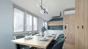 A modern dining area with a wooden table, chairs, and a ceiling light fixture.