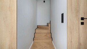 A wooden staircase with white walls and a ceiling light fixture.