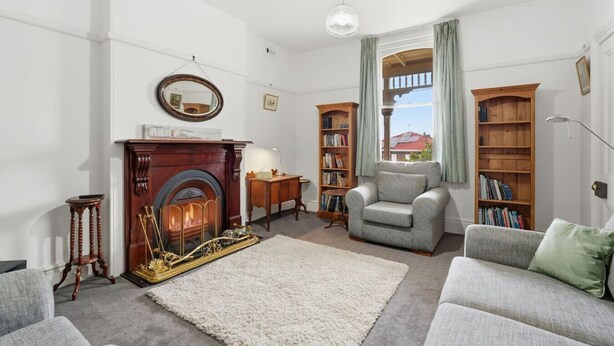 Ein Wohnzimmer mit Kamin, Bücherregalen, einem Sofa und Blick durch ein Fenster.