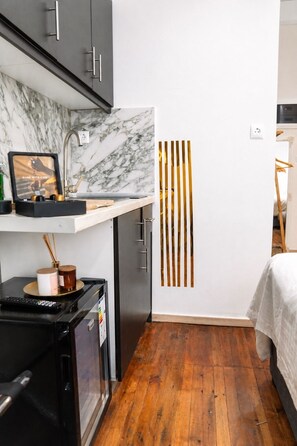 A compact kitchen with a marble backsplash, a black refrigerator, and a wooden floor. - D-Suites – Aristotelous Square Studio, Thessaloniki Centre (Thessaloniki)