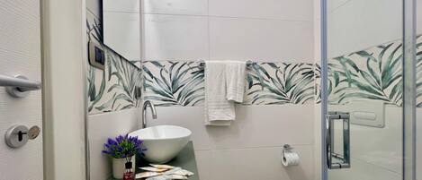 A bathroom with a white sink, a toilet, and a shower area.
