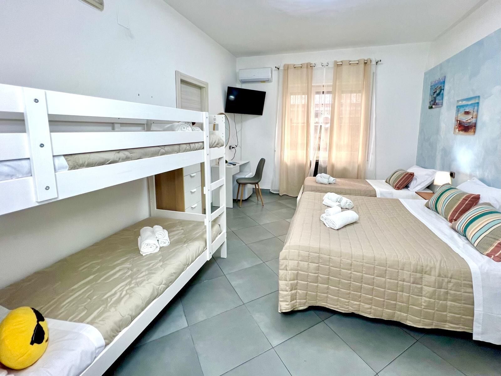 A hotel room with bunk beds, a desk, a chair, and a television.
