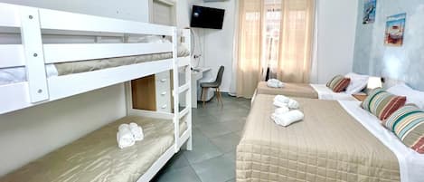 A hotel room with bunk beds, a desk, a chair, and a television.