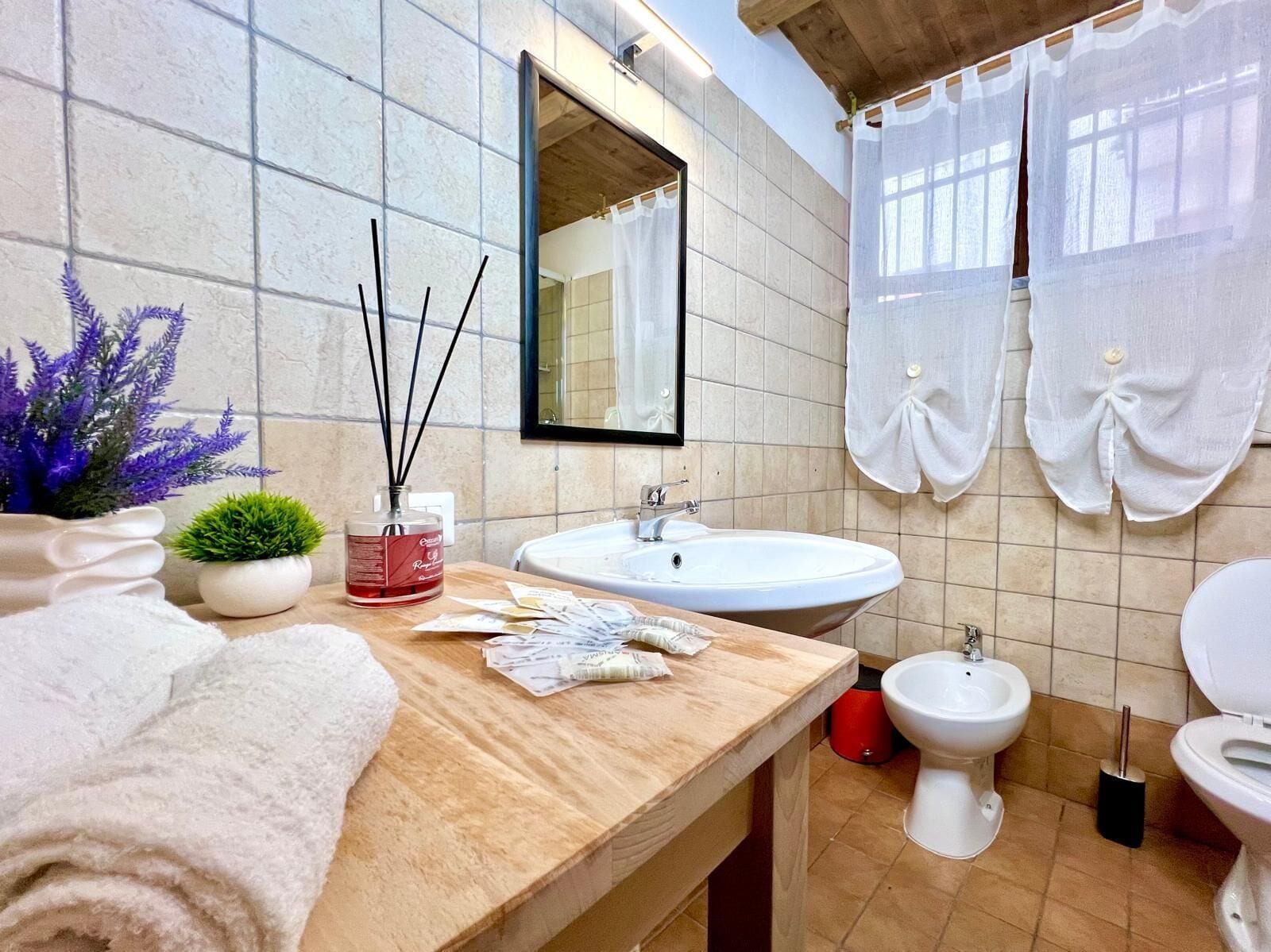 Une salle de bain avec un meuble-lavabo en bois, un miroir, un lavabo, un bidet et des toilettes.