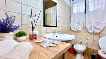 Une salle de bain avec un meuble-lavabo en bois, un miroir, un lavabo, un bidet et des toilettes.