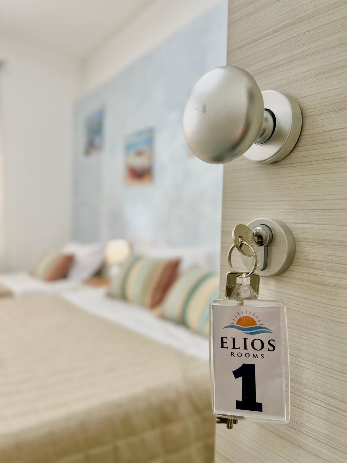Een hotelkamer met een bed, een deur met een sleutelhanger en een muur met een schilderij.
