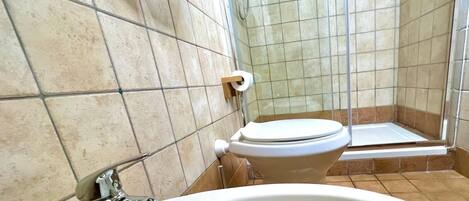 Un baño con lavamanos blanco, inodoro y zona de ducha.