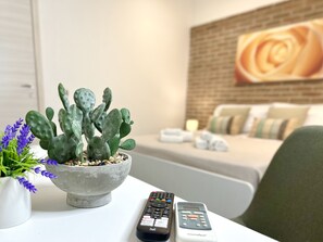A hotel room with a bed, a remote control, a cactus, and a painting on the wall. - Elios Rooms Tro (Tropea)