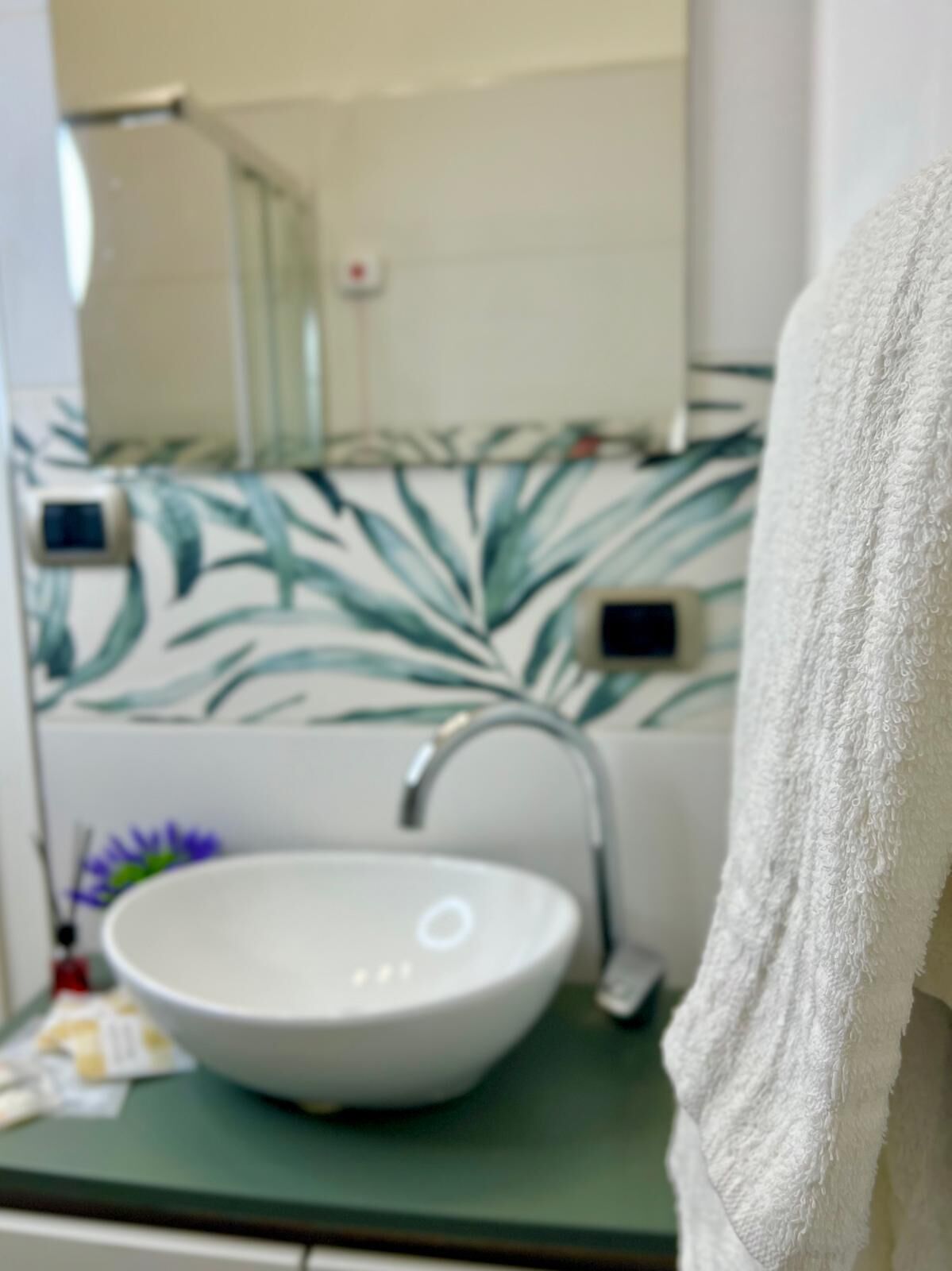 A bathroom with a white sink, a mirror, and a green countertop.
