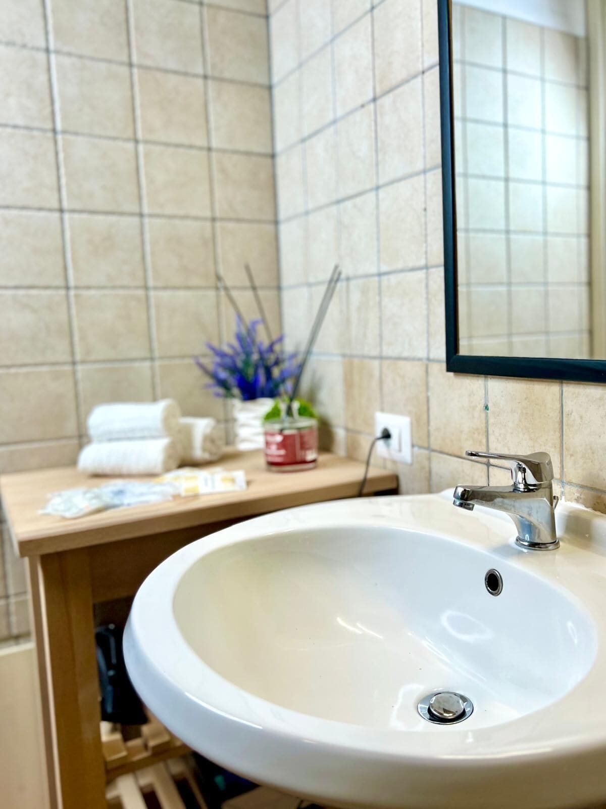 Un baño con lavamanos blanco, un espejo y un perchero para toallas.