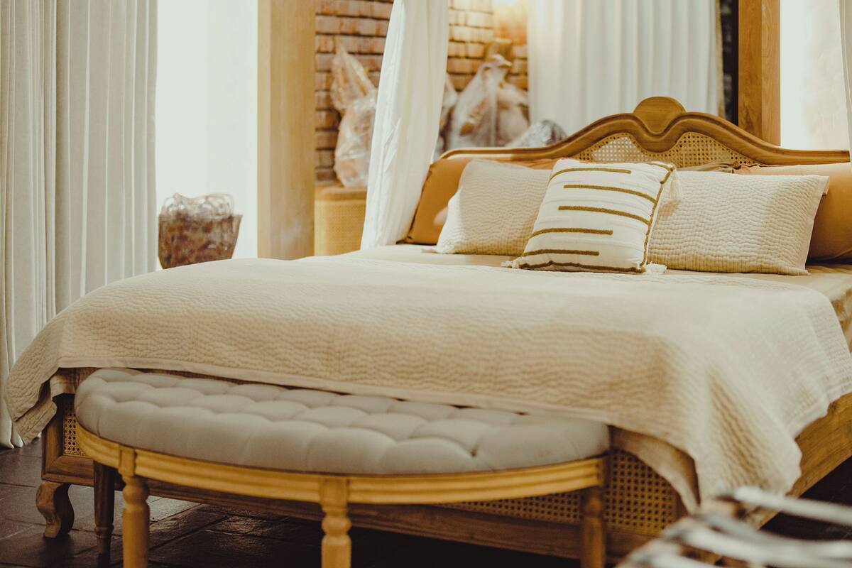 Un letto a baldacchino, una testata in legno e una panca.