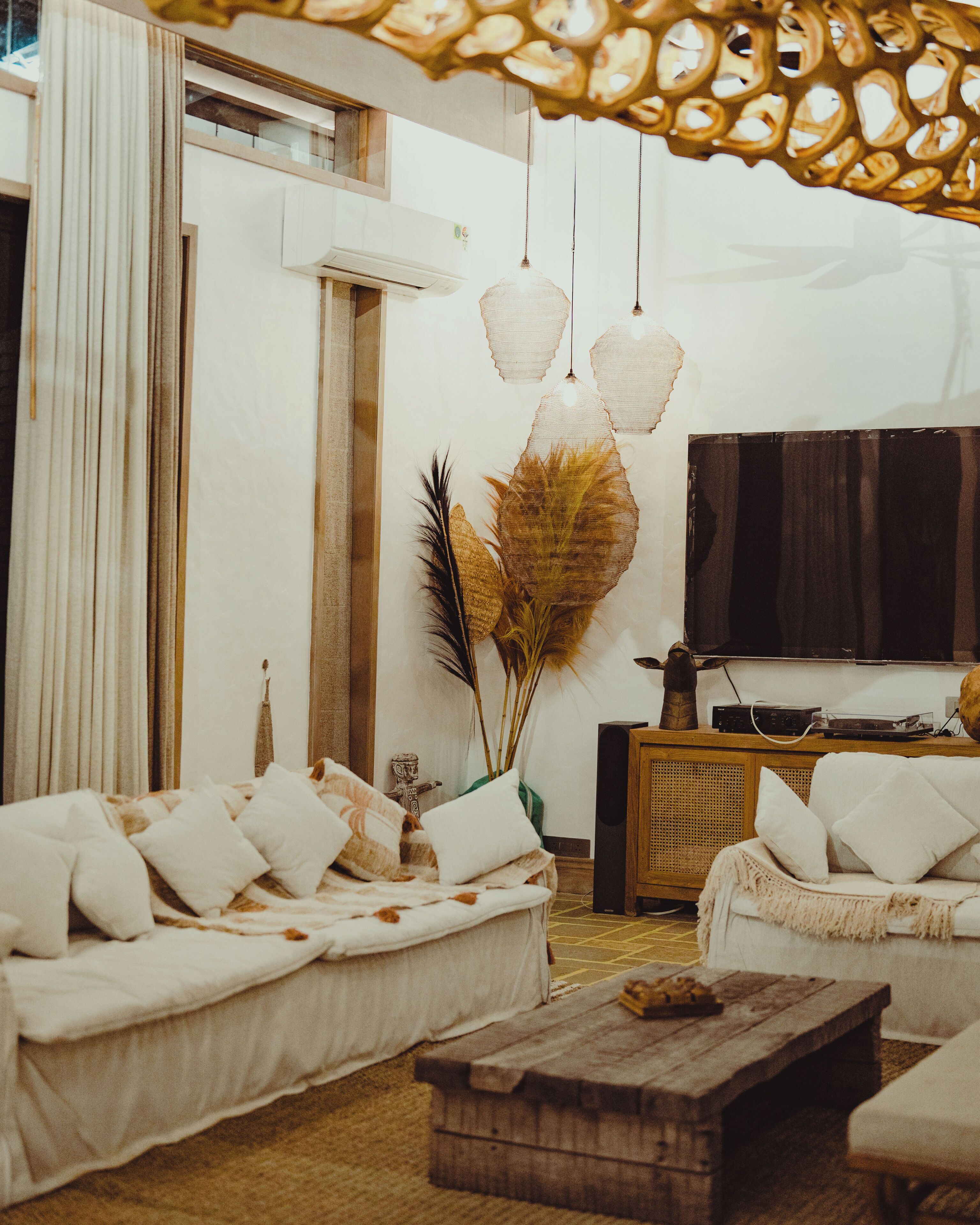 A living room with a sofa set, a wooden coffee table, a television, and decorative plants.