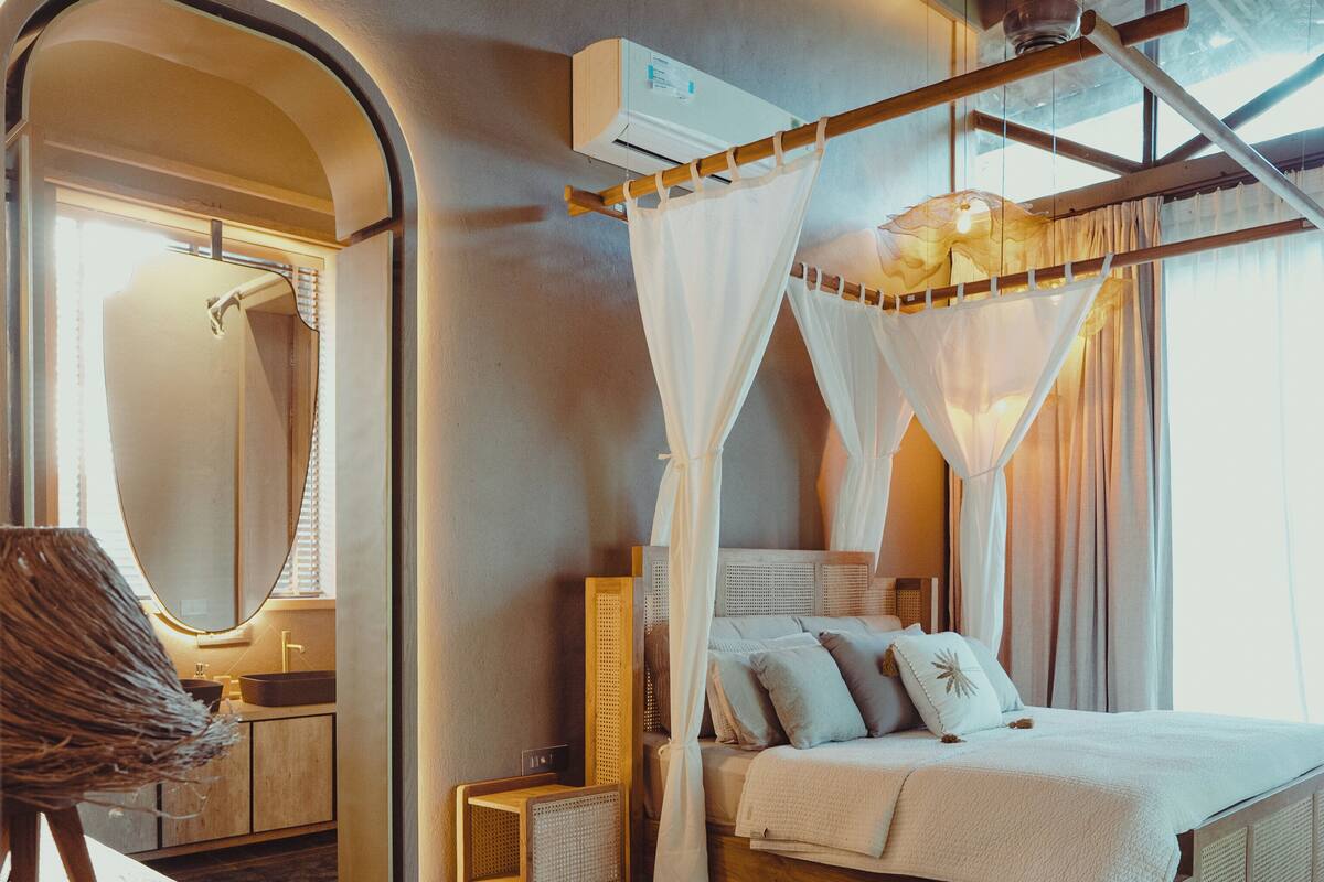 Una camera da letto con un letto a baldacchino, una testiera in legno, un comodino e uno specchio.