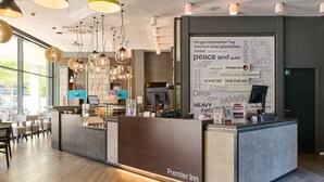 A hotel reception area with a modern design, a reception desk, and a large window providing natural light. - Premier Inn München City West (Munich)