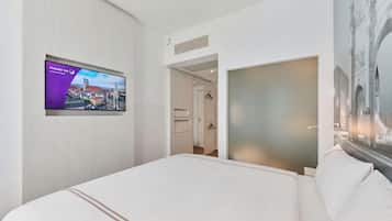 Una habitació d'hotel amb un llit, una televisió penjada a la paret i una porta que dona a un bany.