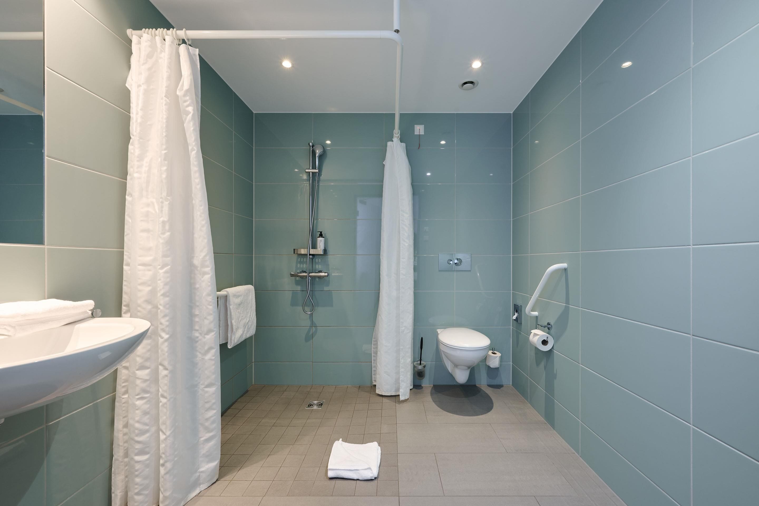 A modern bathroom with a shower, toilet, and sink.