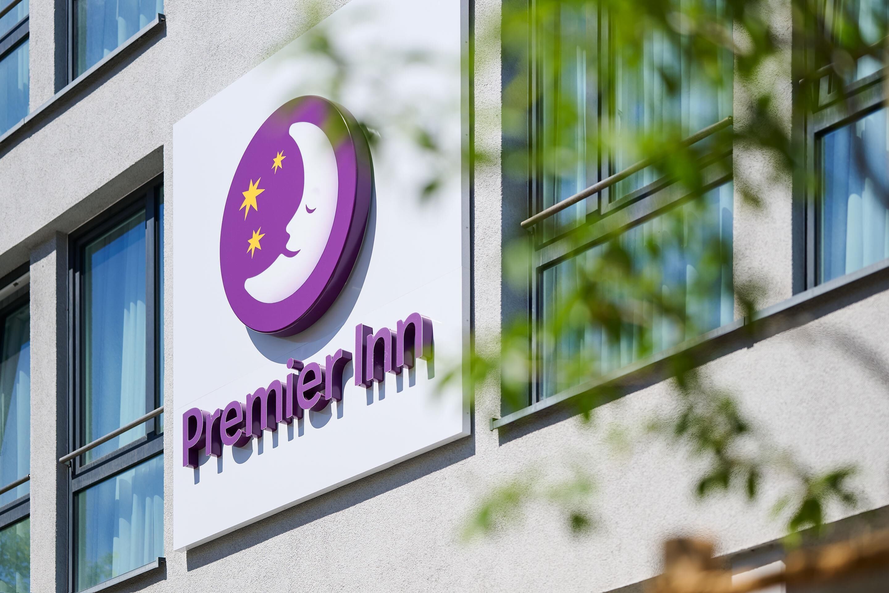 A hotel sign with a purple logo and the name 'Premier Inn' on a building facade.