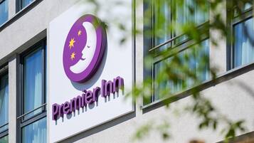 A hotel sign with a purple logo and the name 'Premier Inn' on a building facade.