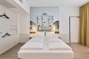 A hotel room with a bed, a wardrobe, a door, and a wall-mounted artwork of a city gate. - Premier Inn München City West (Munich)