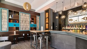 A bar area with a counter, stools, and a bookshelf with books and decorative items. - Premier Inn München City West (Munich)