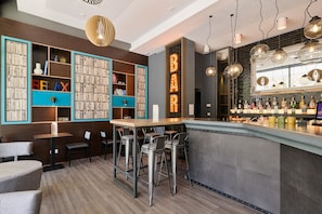 Een bar met een toonbank, krukken en een boekenkast vol boeken en decoratieve objecten.