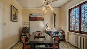 A dining area with a chessboard, chairs, a table, a ceiling fan, a radiator, and a window with decorative glass. - Exclusive villa with view, garden, bbq, pets allowed and parking space (Montefalco)