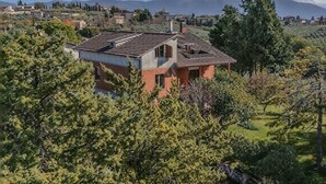 A house with a sloped roof, surrounded by greenery and hills in the background. - Exclusive villa with view, garden, bbq, pets allowed and parking space (Montefalco)