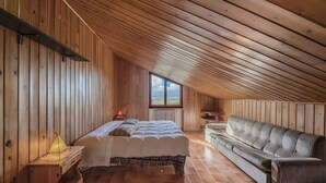 A wooden room with a bed, a sofa, a window, and a radiator. - Exclusive villa with view, garden, bbq, pets allowed and parking space (Montefalco)