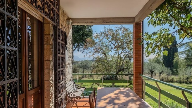 An outdoor patio with a table and chairs, a view of greenery, and a decorative metal fence. - Exclusive villa with view, garden, bbq, pets allowed and parking space (Montefalco)