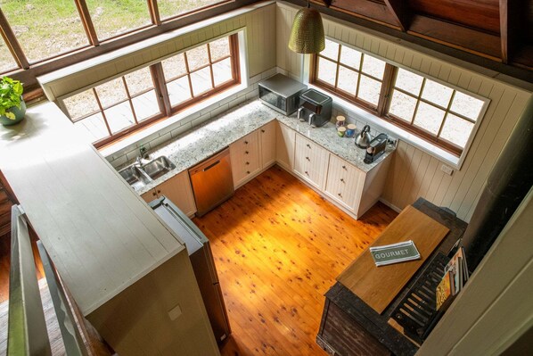 Una cucina con pavimento in legno, un lavello, armadietti e una finestra con vista.
