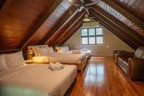 Una stanza con due letti, soffitto in legno, una finestra e un divano in pelle marrone.