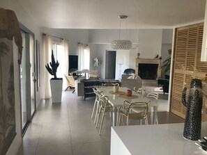Un salon moderne comprenant un coin repas, une cheminée et une grande fenêtre agrémentée de rideaux.
