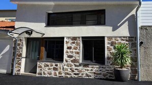 A two-story building with a stone facade, a single entrance with a door, and a potted plant outside.