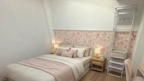 A bedroom with a bed, bedside tables, a chair, and a built-in shelf unit.