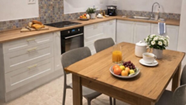 A modern kitchen with white cabinets, a wooden dining table, and a breakfast setting.
