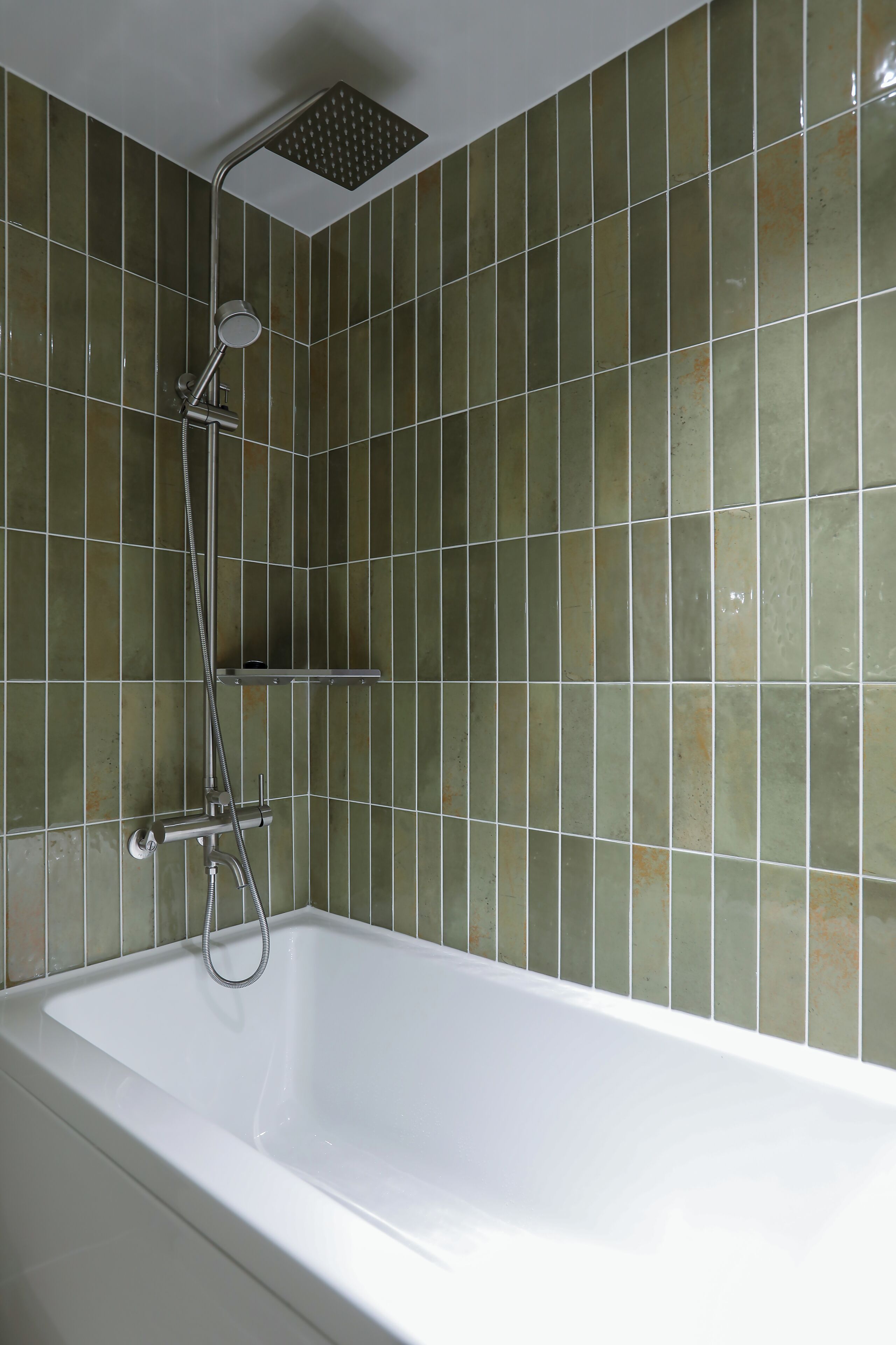 A bathroom with a bathtub, shower, and tiled walls.