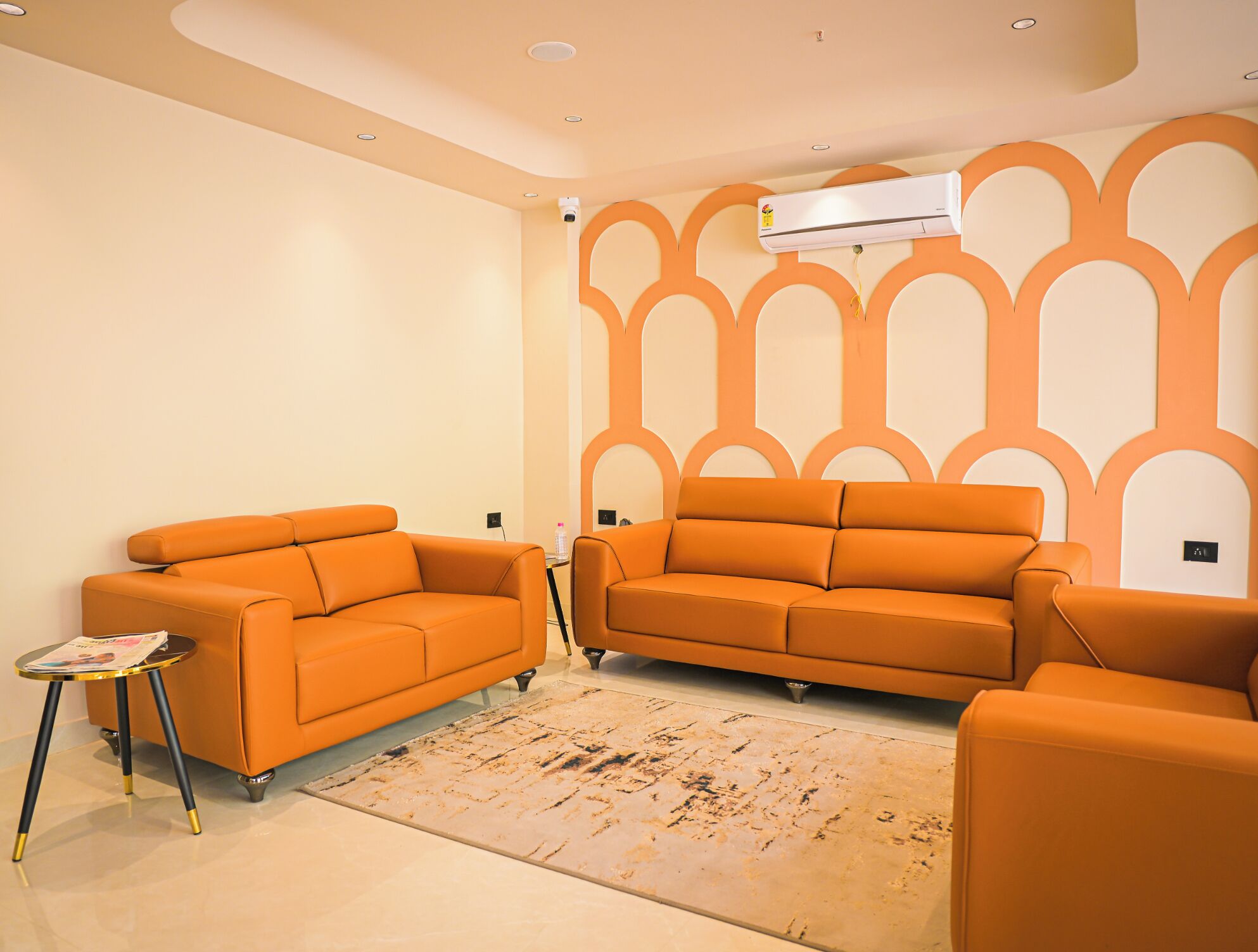 Ein Wohnzimmer mit zwei orangenen Sofas, einem kleinen runden Tisch und einem Teppich mit Muster.