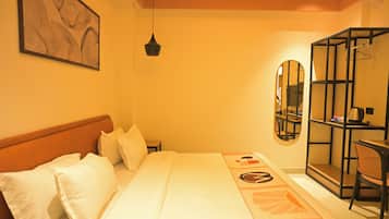 Habitación de hotel con cama, mesita de noche, espejo, lámpara colgante y armario.