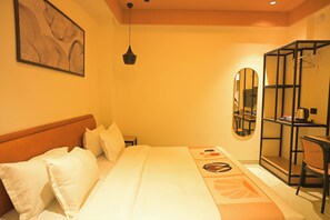 Habitación de hotel con cama, mesita de noche, espejo, lámpara colgante y armario.