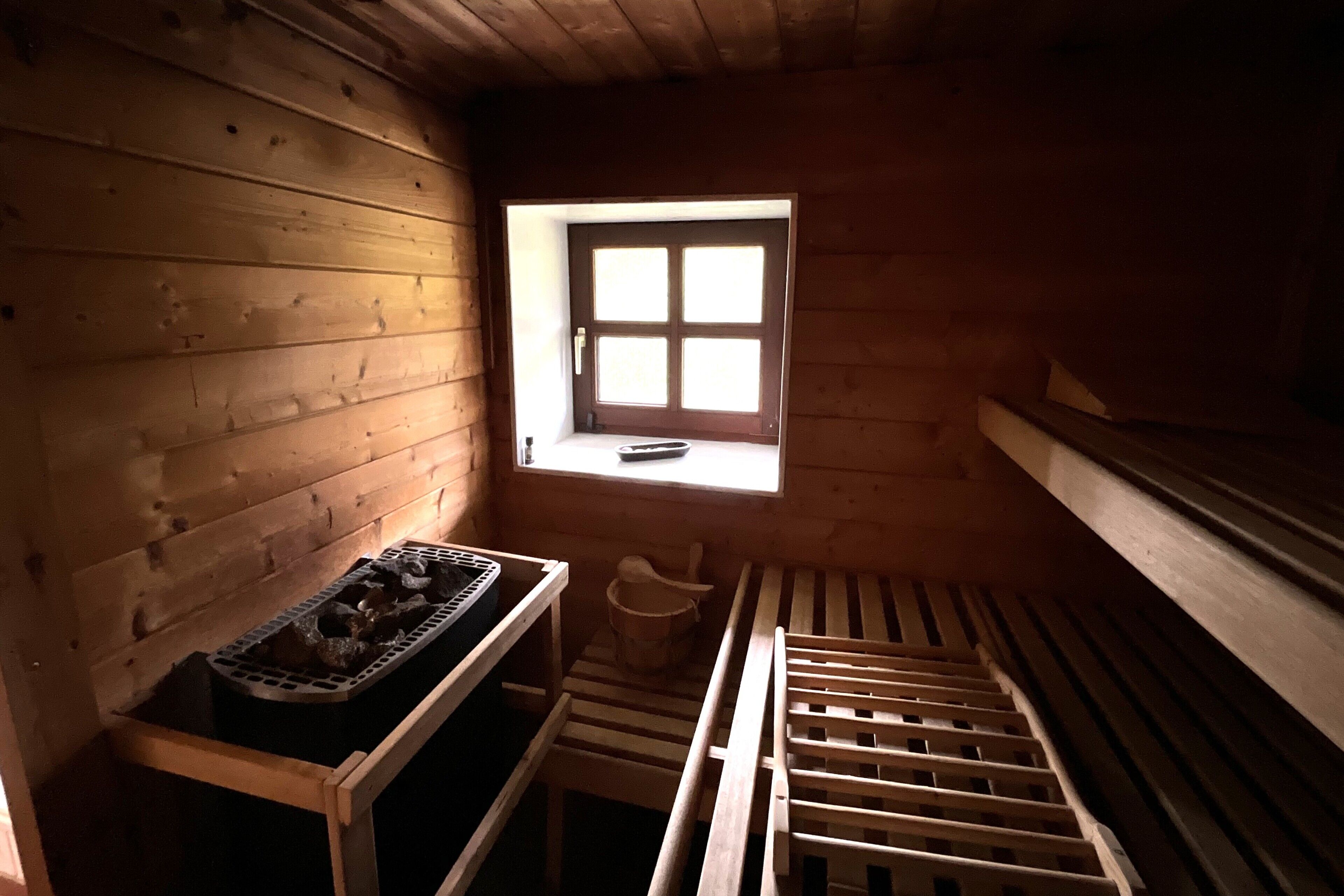 A wooden cabin with a window, a wooden bench, and a small table with a tray.