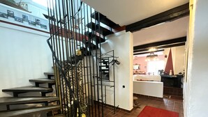 Eine Treppe mit Metallgeländer, ein roter Teppich auf dem Boden und eine Küche im Hintergrund.