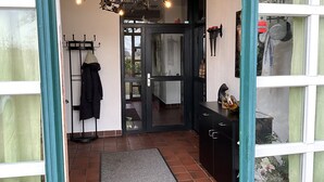 Ein Durchgang zu einem Raum mit Fliesenboden, einem Kleiderständer, einer dekorativen Metallleuchte und einem Schrank mit einer kleinen Statue.