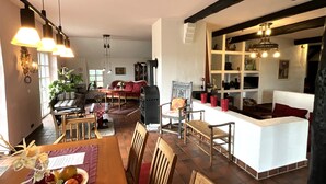Ein gemütliches Wohnzimmer mit Kamin, Essbereich mit Holzmöbeln und eine Küchenzeile mit weißen Schränken.