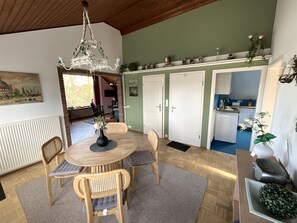 Ein Essbereich mit einem runden Tisch, vier Stühlen, einer Deckenleuchte und einem Gemälde an der Wand.